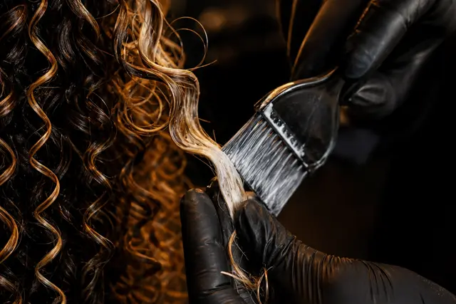 Cabelo cacheado escuro volumoso com mechas mais claras sob luz dourada